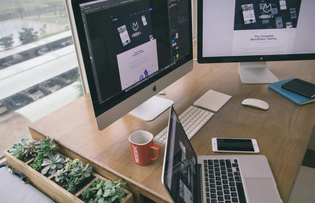 Sleek office desk setup featuring Apple computers and greenery for a modern work environment.